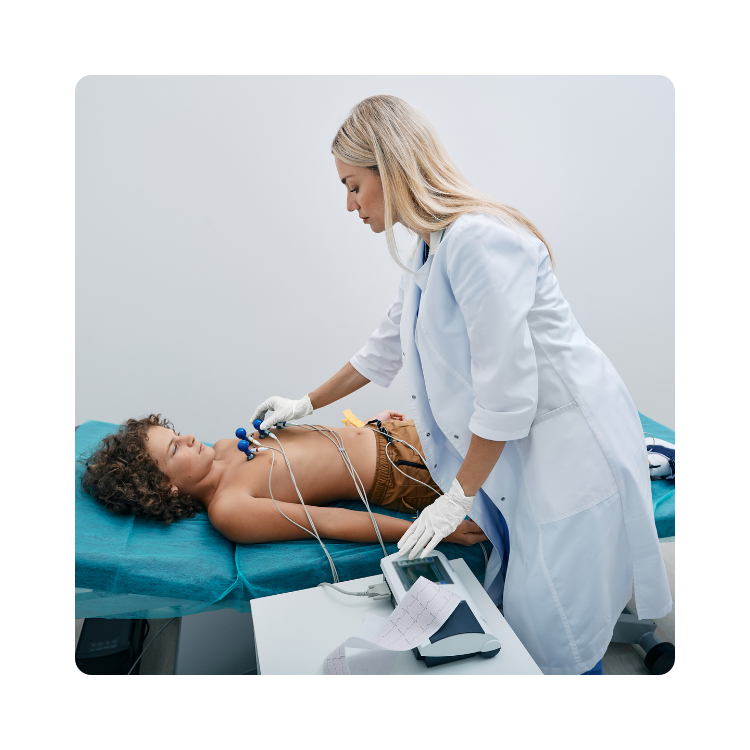 diagnostyka w gabinecie zabiegowym w promed Lekarka wykonująca badanie EKG młodemu pacjentowi leżącemu na kozetce w gabinecie