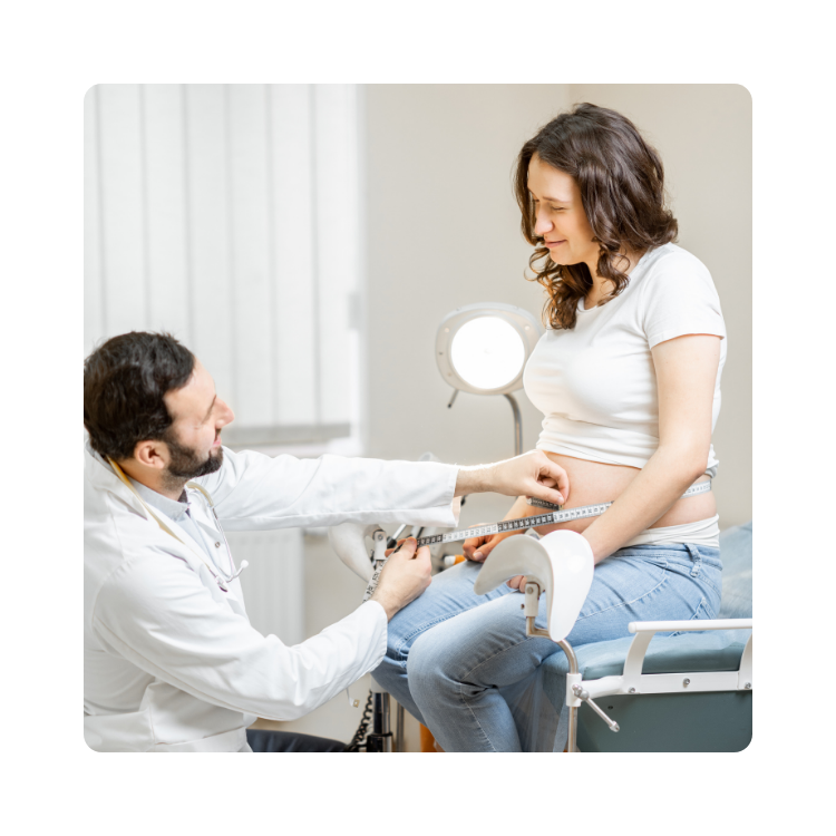 Lekarz rodzinny mierzy obw&oacute;d brzucha u uśmiechniętej pacjentki w ciąży, siedzącej na kozetce podczas wizyty kontrolnej