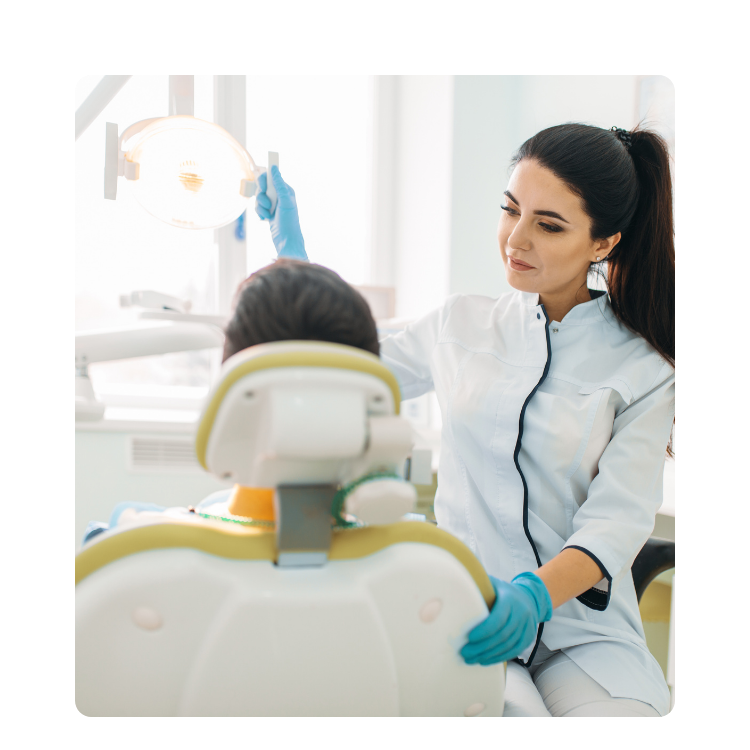 Dentystka rozmawiająca z dzieckiem siedzącym na fotelu stomatologicznym w gabinecie