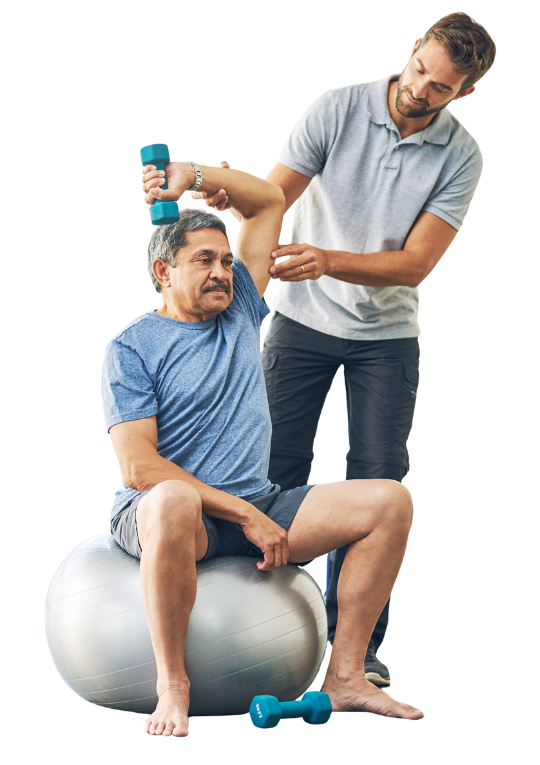zdjęcie do poradni rehabilitacji Fizjoterapeuta asystuje starszemu mężczyźnie podczas ćwiczenia ramienia z hantlem, siedzącemu na piłce rehabilitacyjnej.