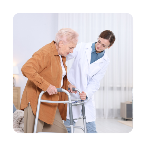 Fizjoterapeutka pomaga starszej kobiecie chodzić przy użyciu balkonika rehabilitacyjnego w jasnym pomieszczeniu.